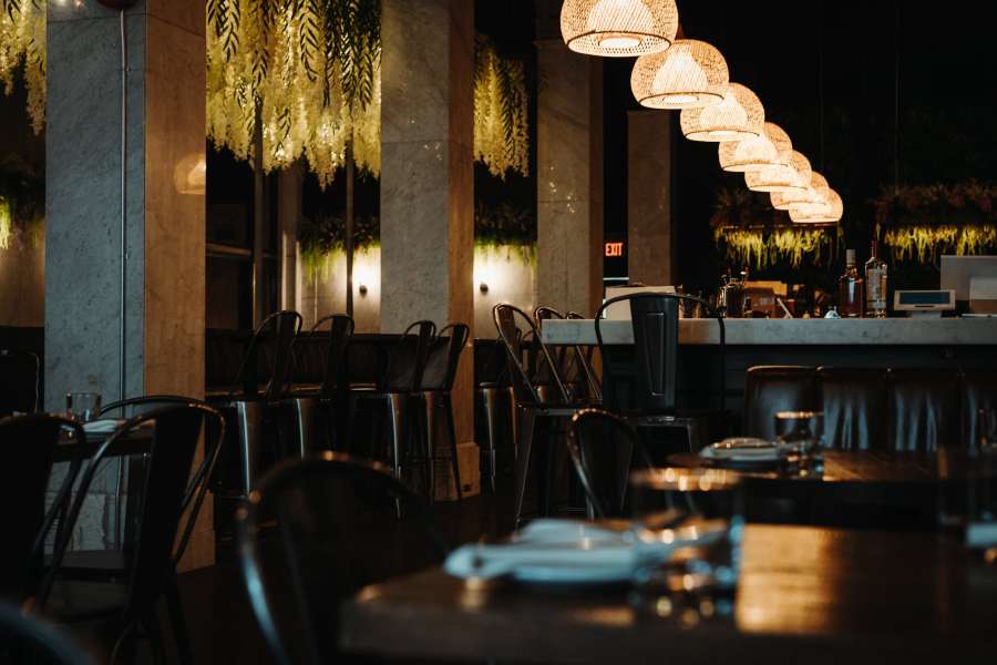 Interior of Commonwealth Winnipeg restaurant featuring stylish lighting, a bar area, and dining tables with elegant decor.